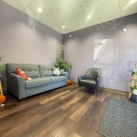 Front office lobby. Grey couch with animal plushies and plants throughout the room.