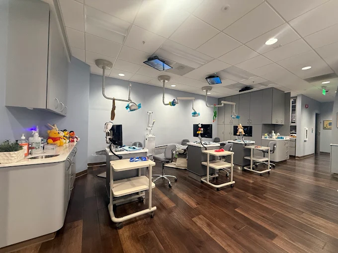 large exam room with three stations. tv's on the ceiling and little stuffed plushies throughout the room