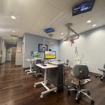 Exam room with stuffed animals hanging from the lights and tvs on the ceiling